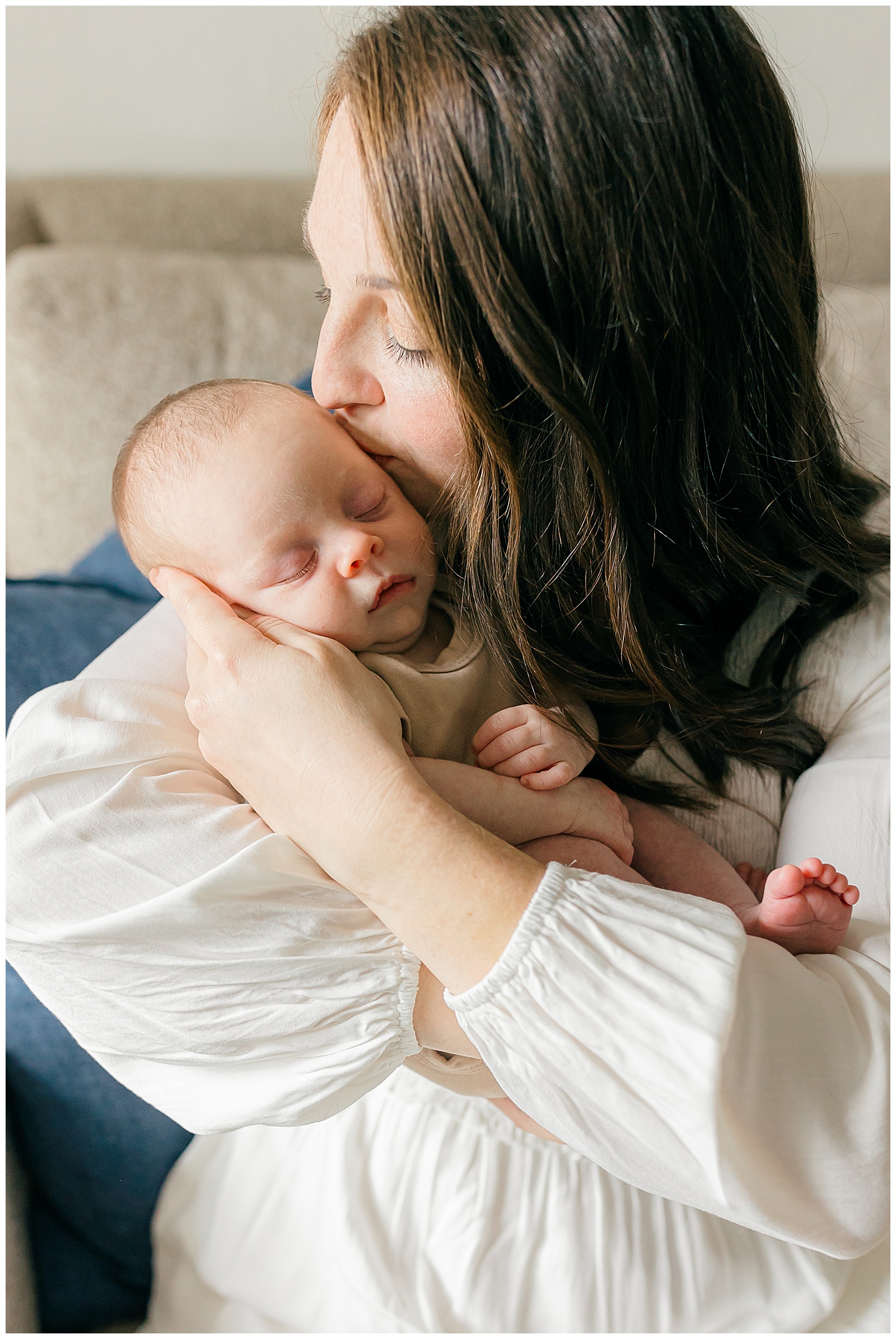 Mother embracing and kissing newborn baby boy on the cheek at In home newborn session in Tampa, Florida